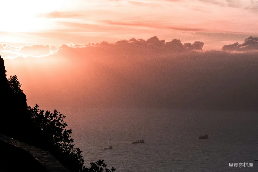 高清摄影  夕阳下，阳光穿透云层洒在海洋上，几艘船在海面上航行。