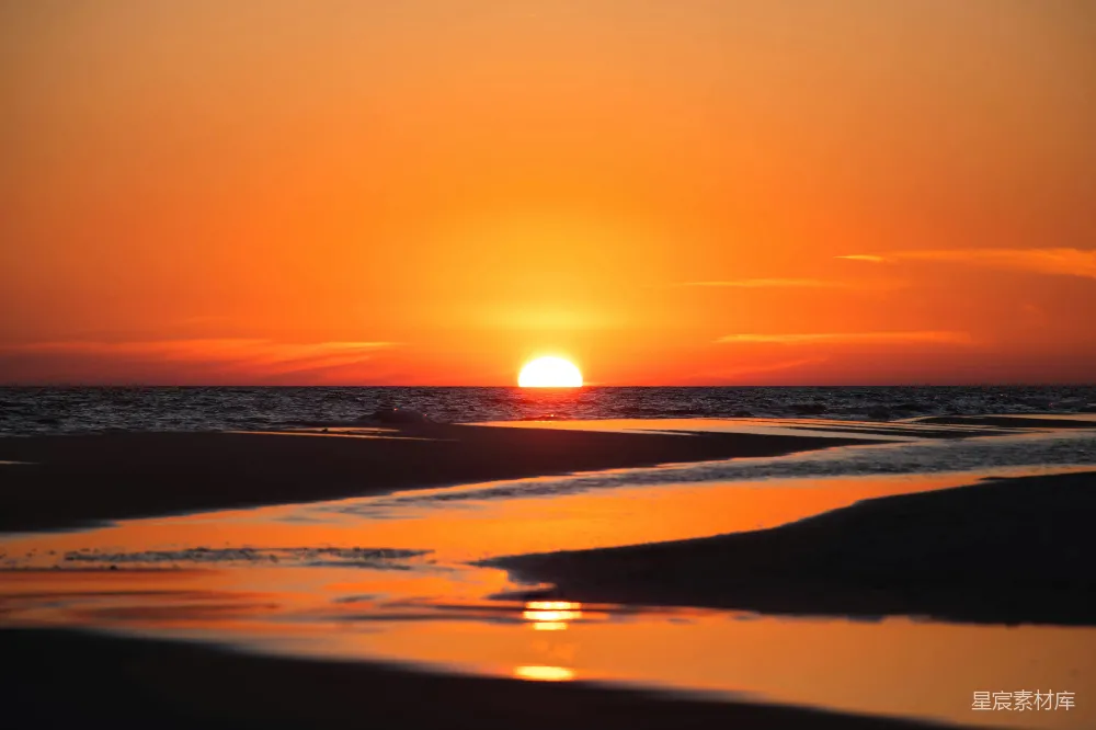 高清摄影  太阳正在海洋上空的海滩上落下。