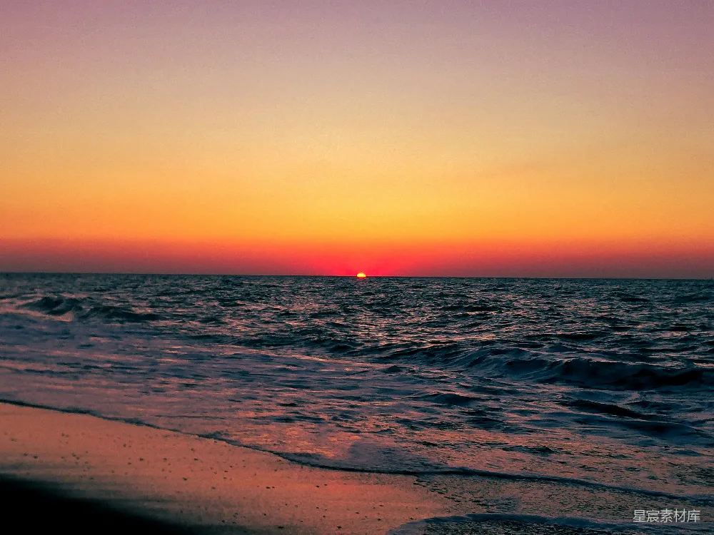 高清摄影  夕阳正在海滩上空的海面上落下。