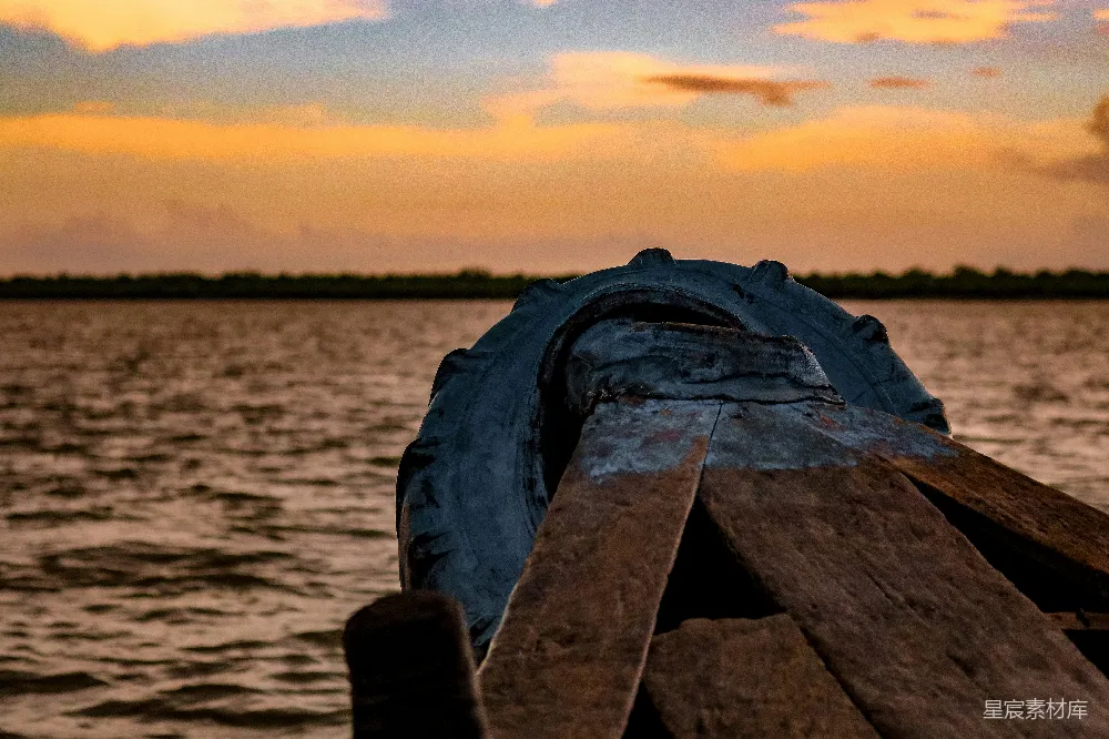 高清摄影  戴着黑色手套的人站在棕色木制码头上，夕阳西下。