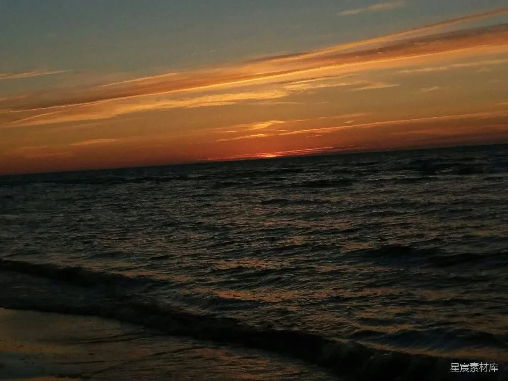 高清摄影  夕阳正挂在海面上的海滩上。