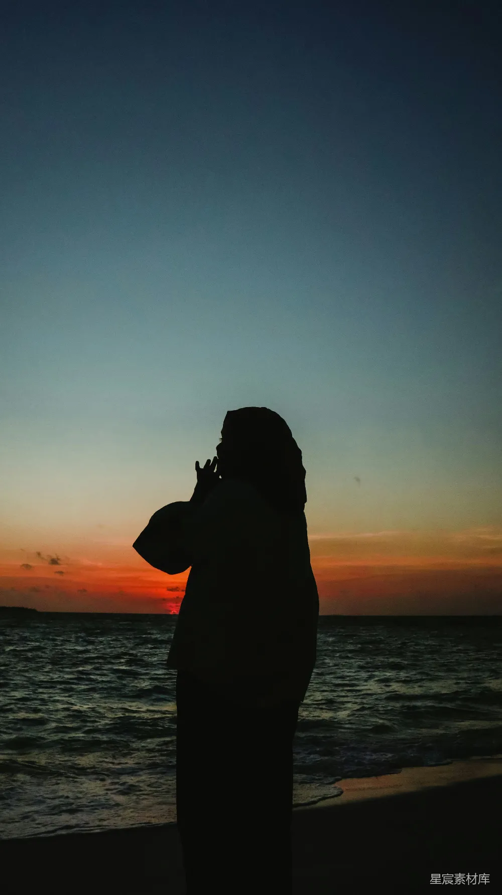 高清摄影  一个站在海滩上的人在夕阳下。