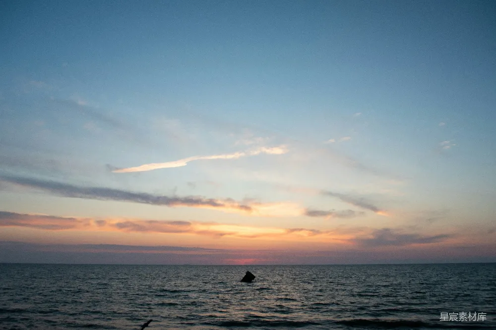 高清摄影  夕阳正投射在海面上，水中有个人。