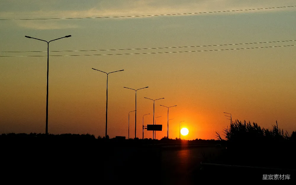 高清摄影  夕阳在远处的路灯后面落下。
