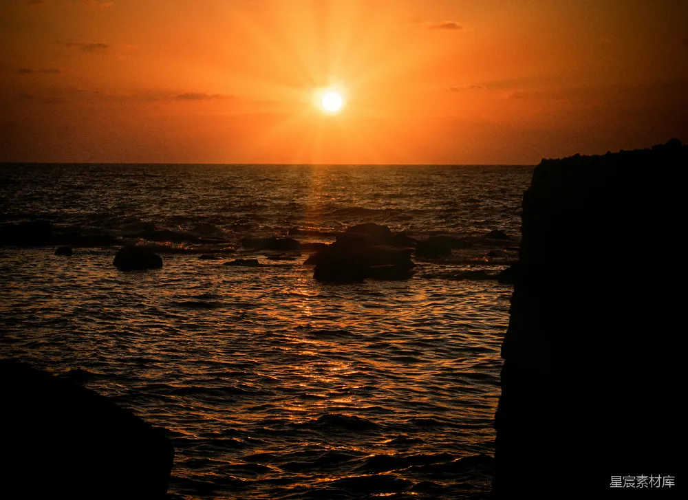 高清摄影  夕阳正缓缓落下，海面的岩石在前景中显得格外突出。