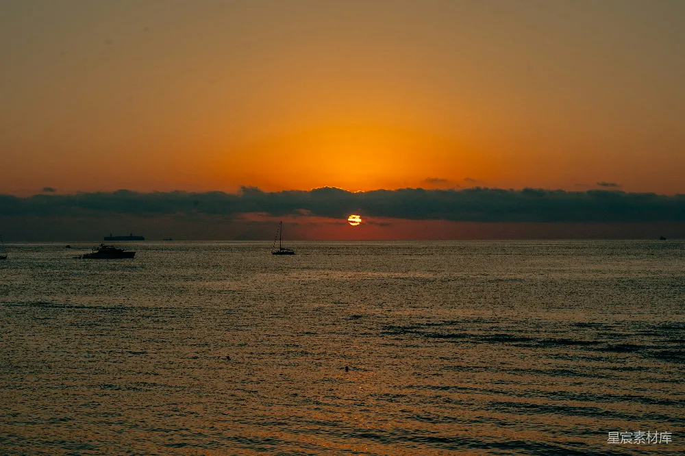高清摄影  大海上的日落景象，船在水中漂浮。