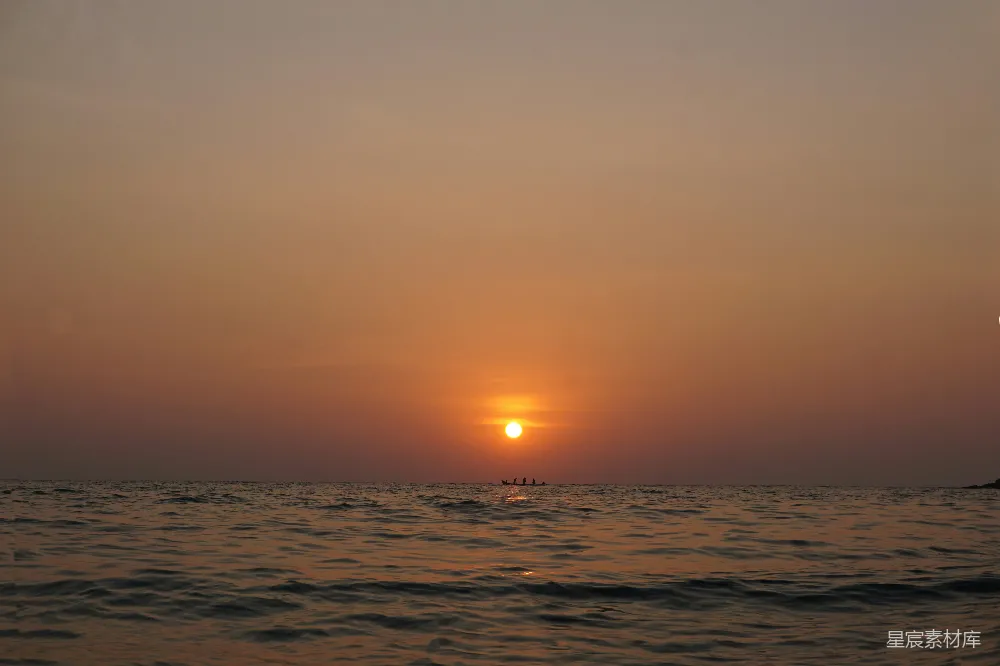 高清摄影  夕阳正挂在海面上，远处有一艘小船。