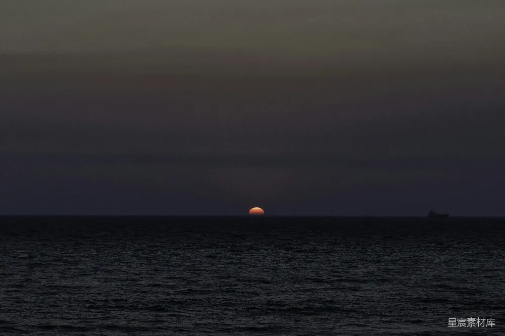 高清摄影  夕阳沉落在一片宁静而漆黑的海洋上。