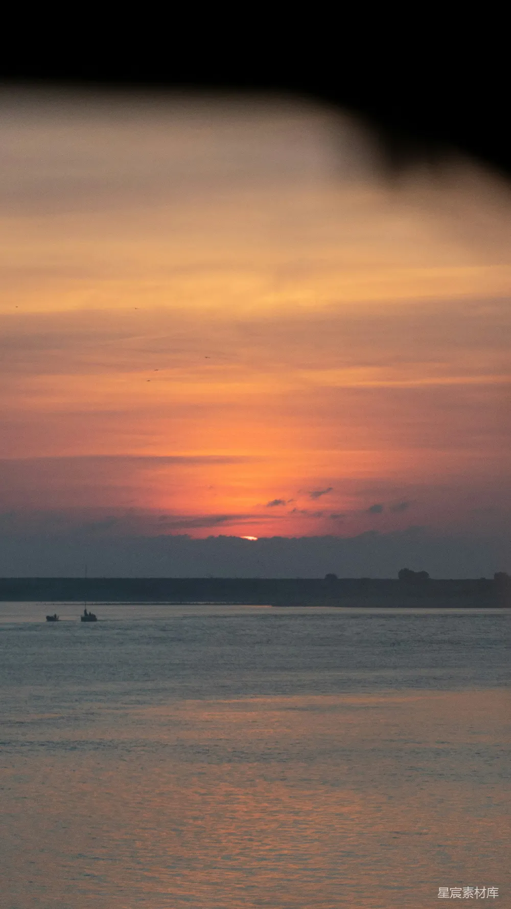 高清摄影  夕阳映照在水面上，远处有一艘小船。