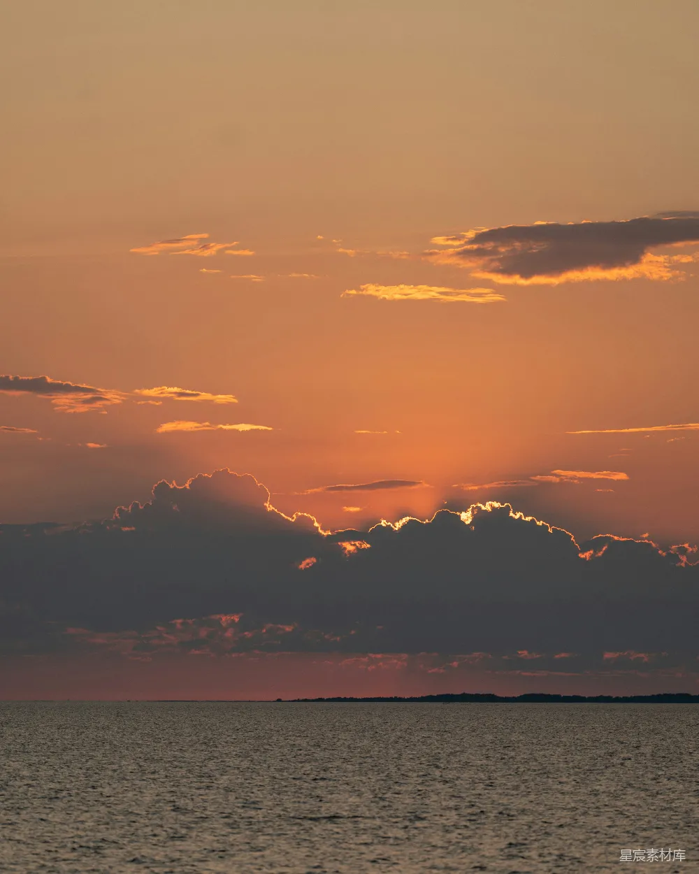 高清摄影  夕阳映照在平静的海洋上，天空中布满了壮观的云彩。