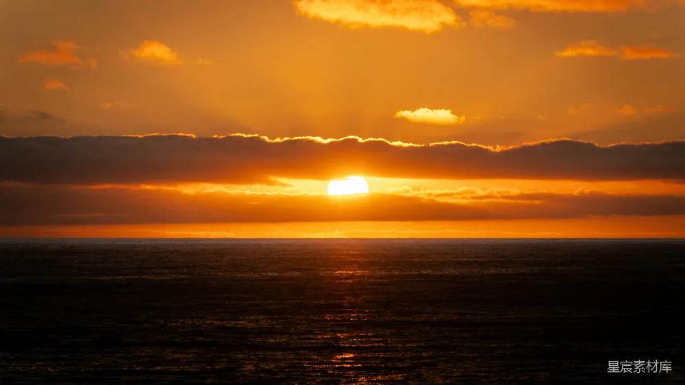 高清摄影  夕阳沉落在一片幽暗而平静的海洋上。
