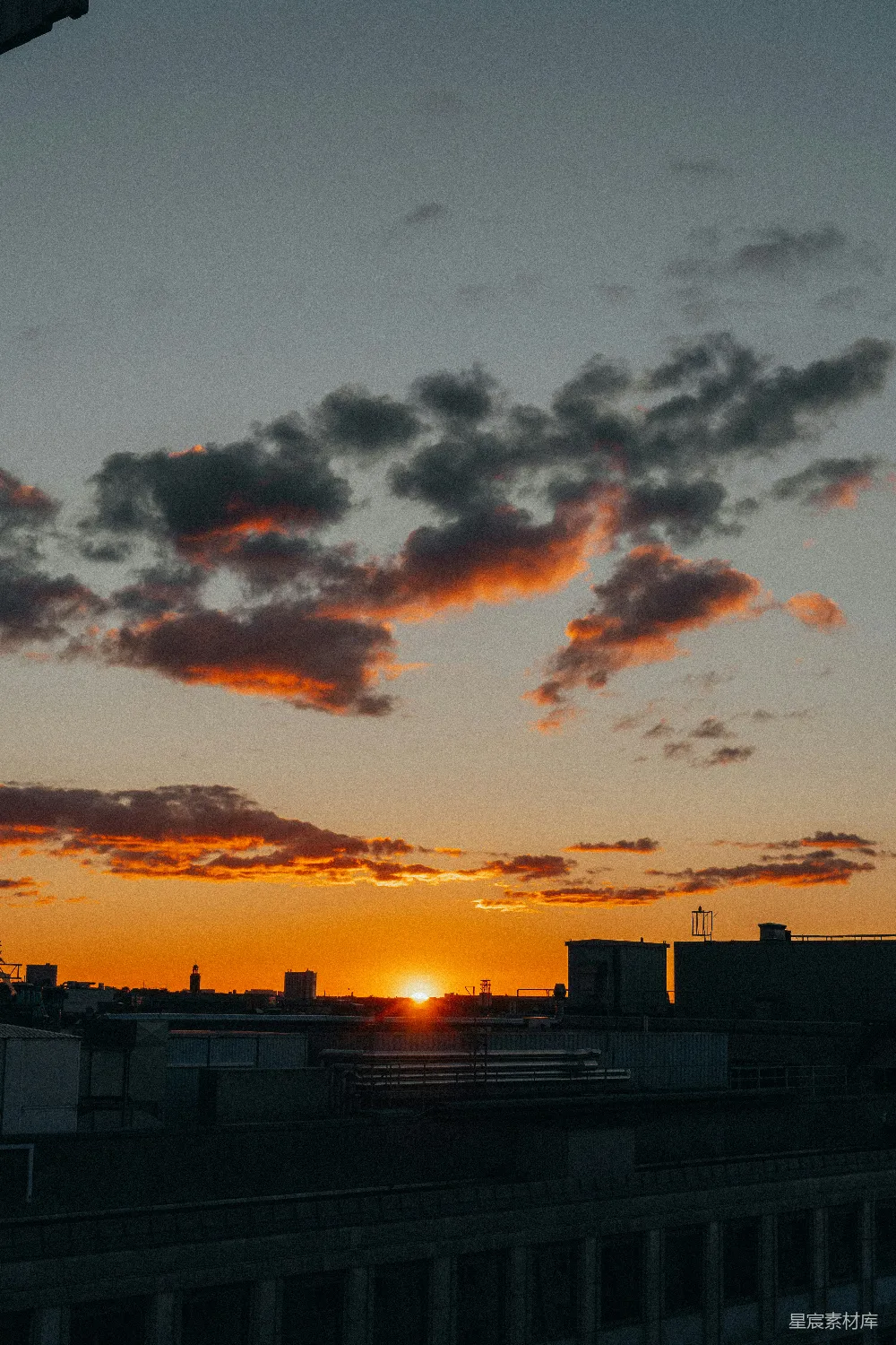 高清摄影  夕阳西下，城市上空布满橙色和深色的云朵。