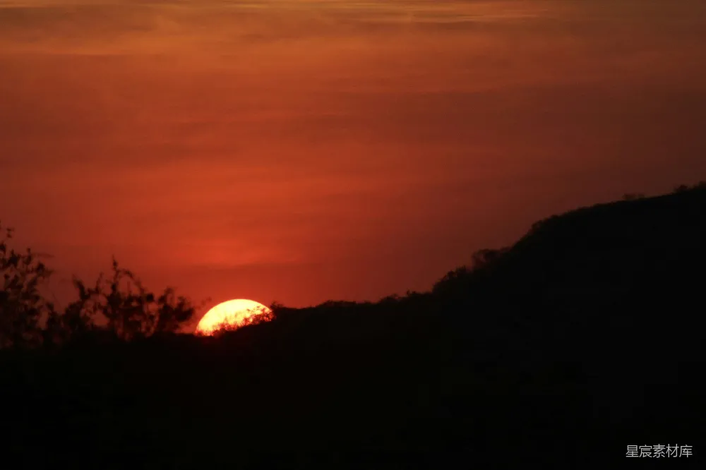 高清摄影  夕阳正在树林覆盖的山丘上落下。