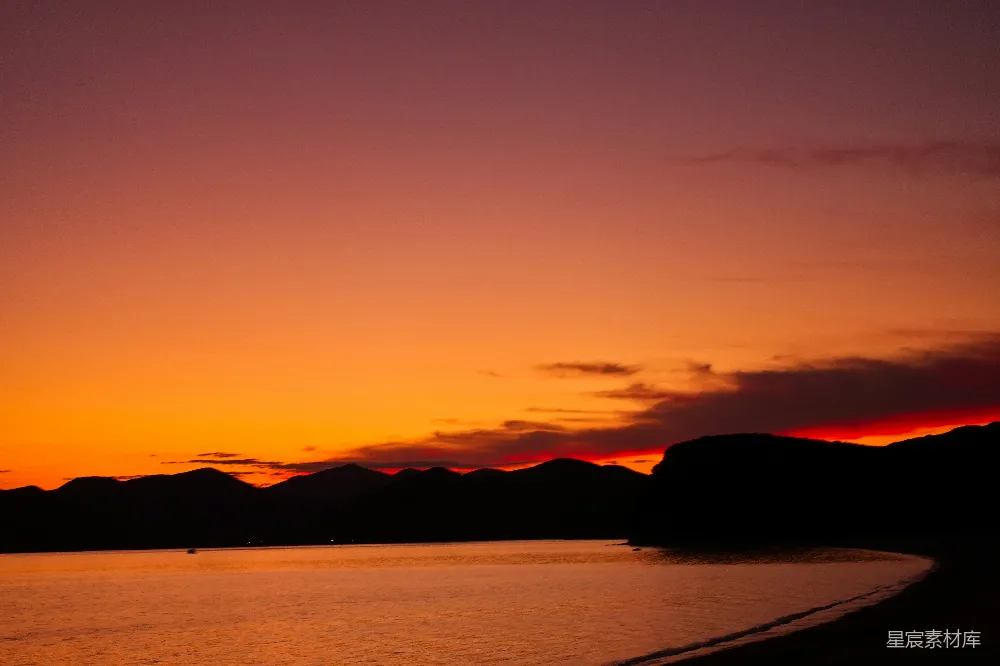 高清摄影  夕阳西下，水面上方有一片山脉。