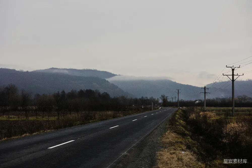 高清摄影  一条长长的空旷道路，背景是连绵的山脉。