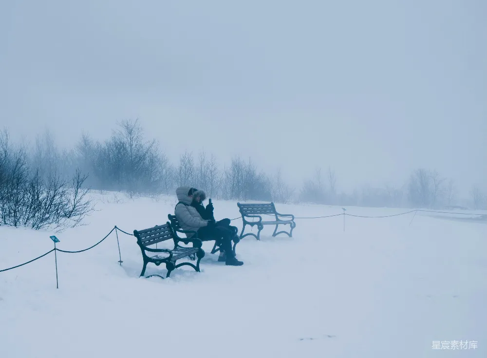 高清摄影 人物 一个人独自坐在雪地里的公园长椅上。