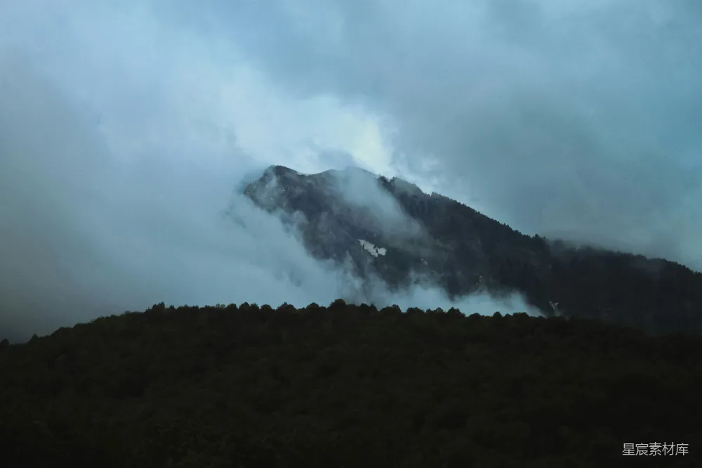 高清摄影  在多云的天气里，一座被雾气和云朵覆盖的山。