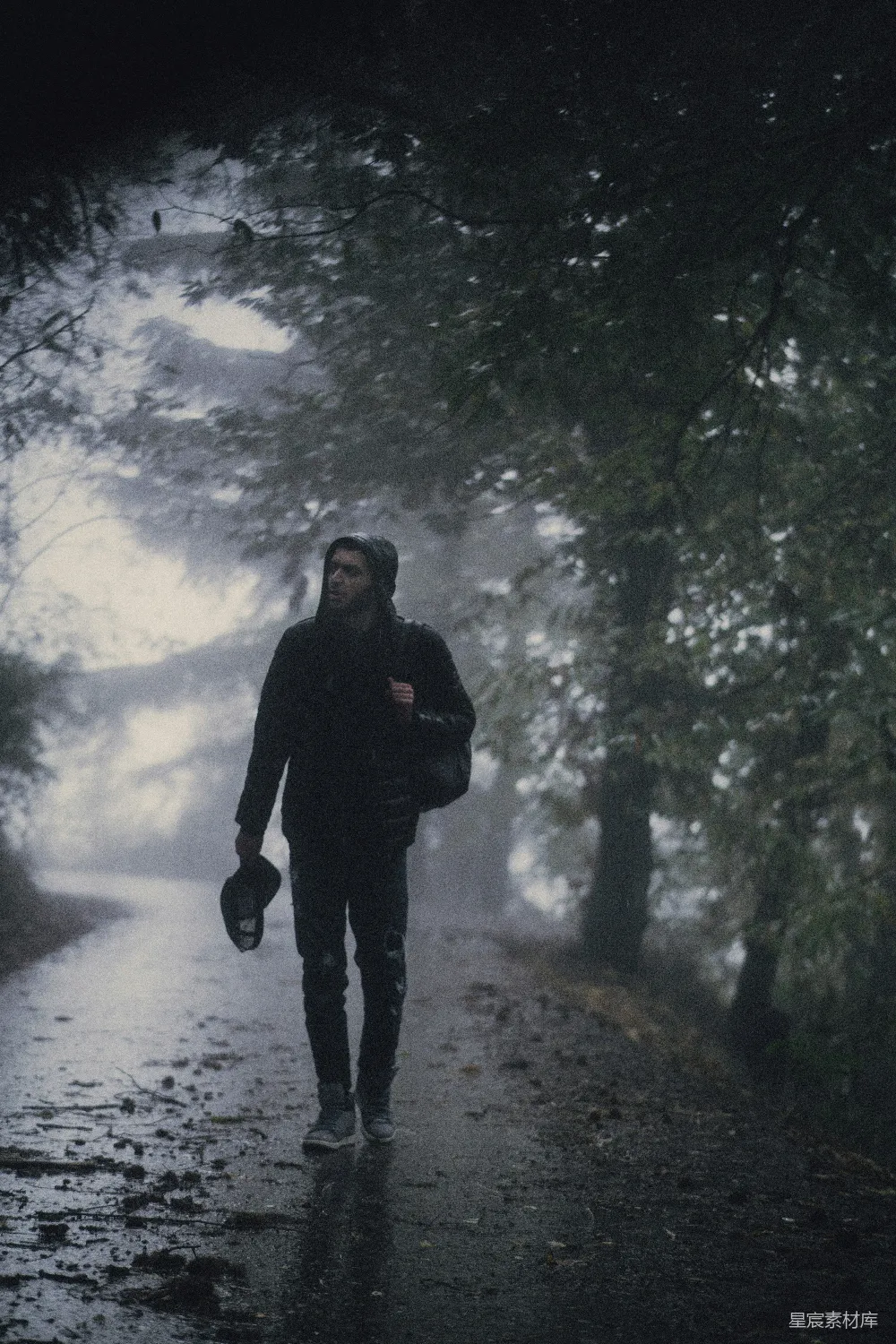 高清摄影  一个男人在雨中沿着马路行走。