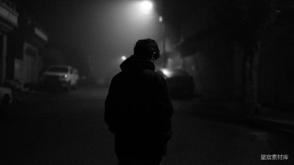高清摄影  一个人在夜晚的雾气中走在街道上。