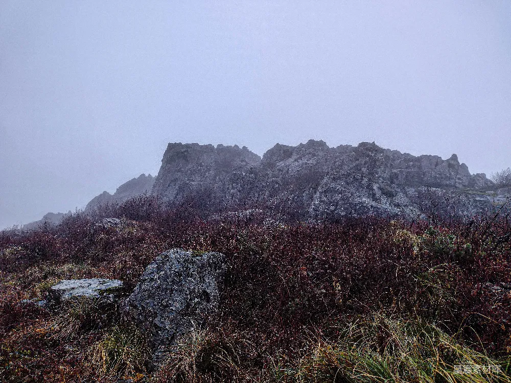 高清摄影  一座岩石山，前景中有草地和岩石。
