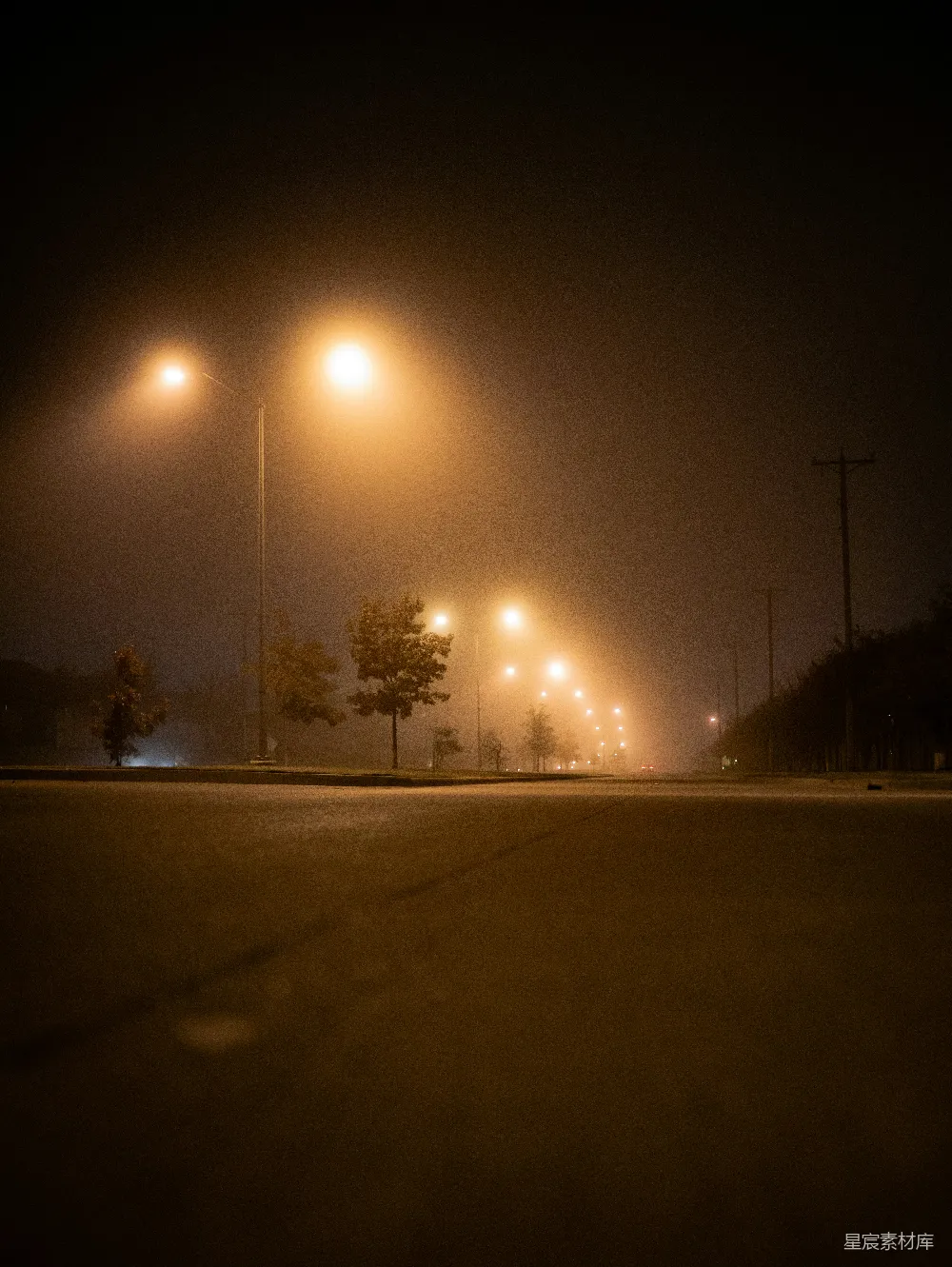 高清摄影  夜晚雾蒙蒙的街道上，路灯亮着。