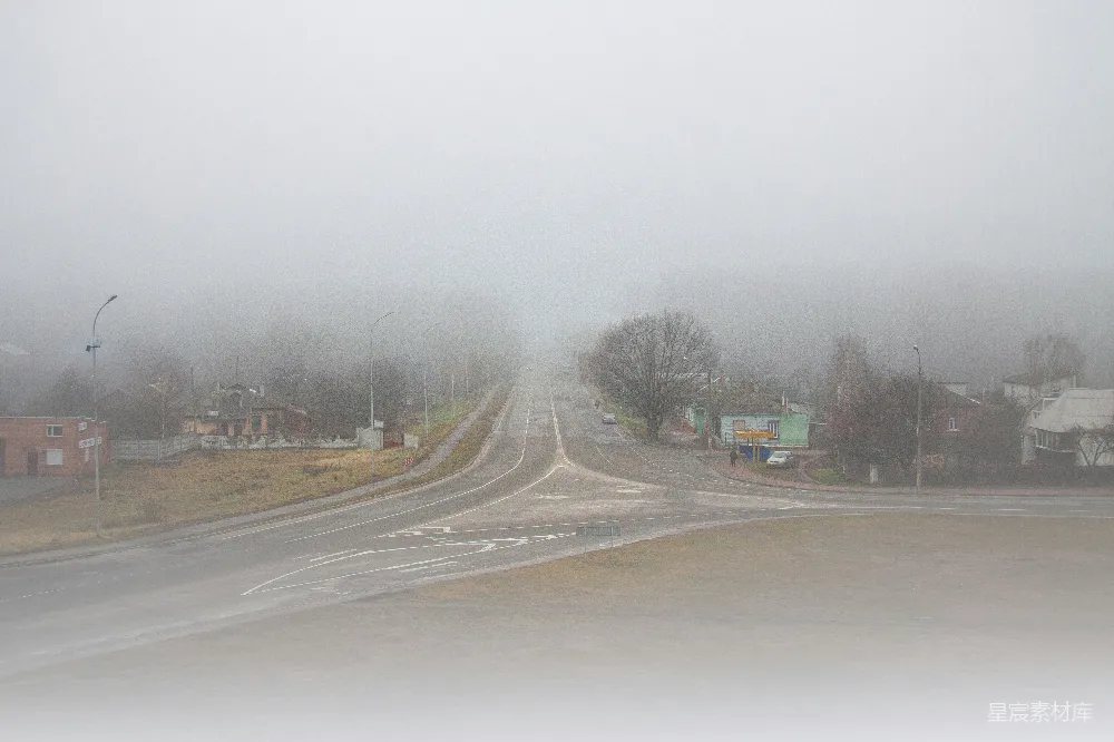 高清摄影  雾蒙蒙的道路交汇处，周围是建筑物和树木。