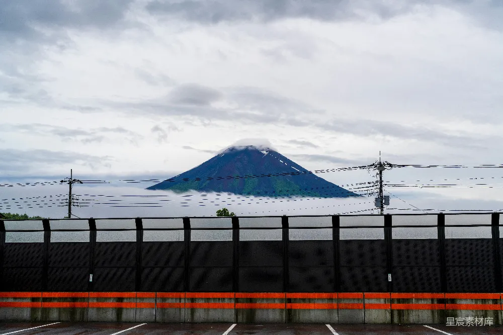 高清摄影  富士山在路障后面的云层中若隐若现。