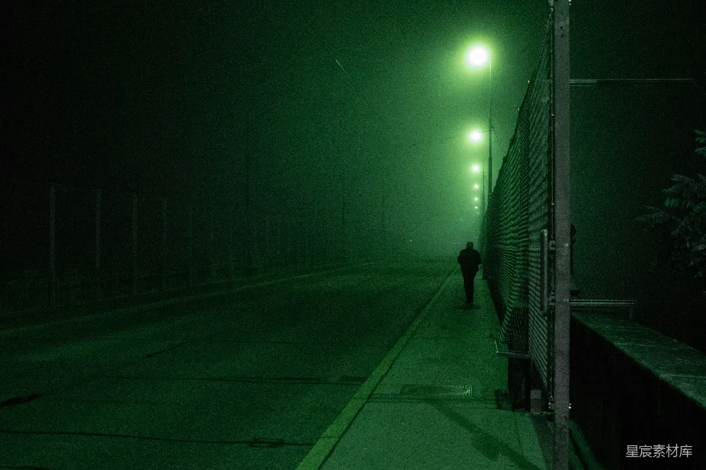 高清摄影 实验性 夜晚，一位穿着黑色夹克的男子在人行道上行走。