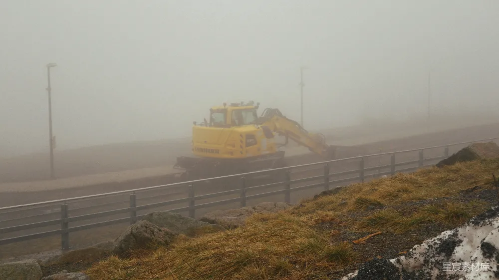 高清摄影  一辆黄色的推土机在雾蒙蒙的天气里沿着道路行驶