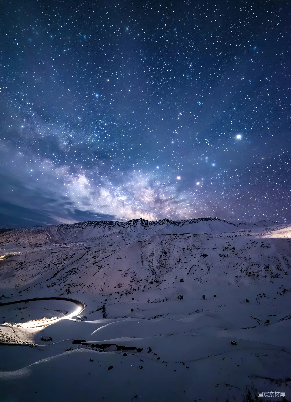 高清摄影  在积雪覆盖的山峰上方，夜空中布满了星星。