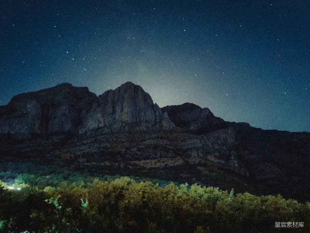 高清摄影  夜空中的星星照耀着一座山。