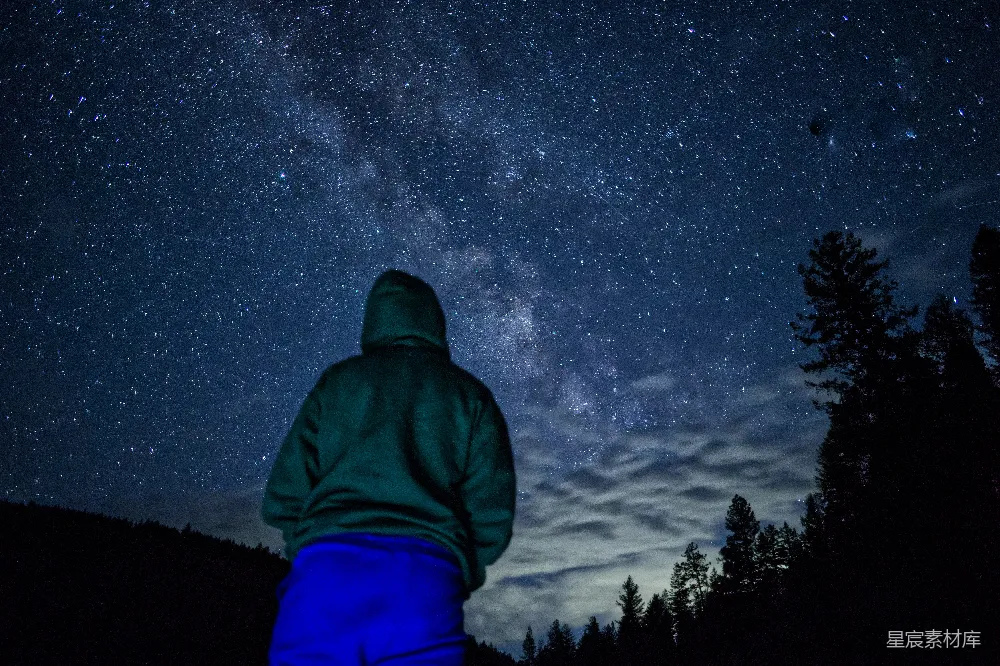 高清摄影  一个穿着绿色夹克的人仰望着夜空。
