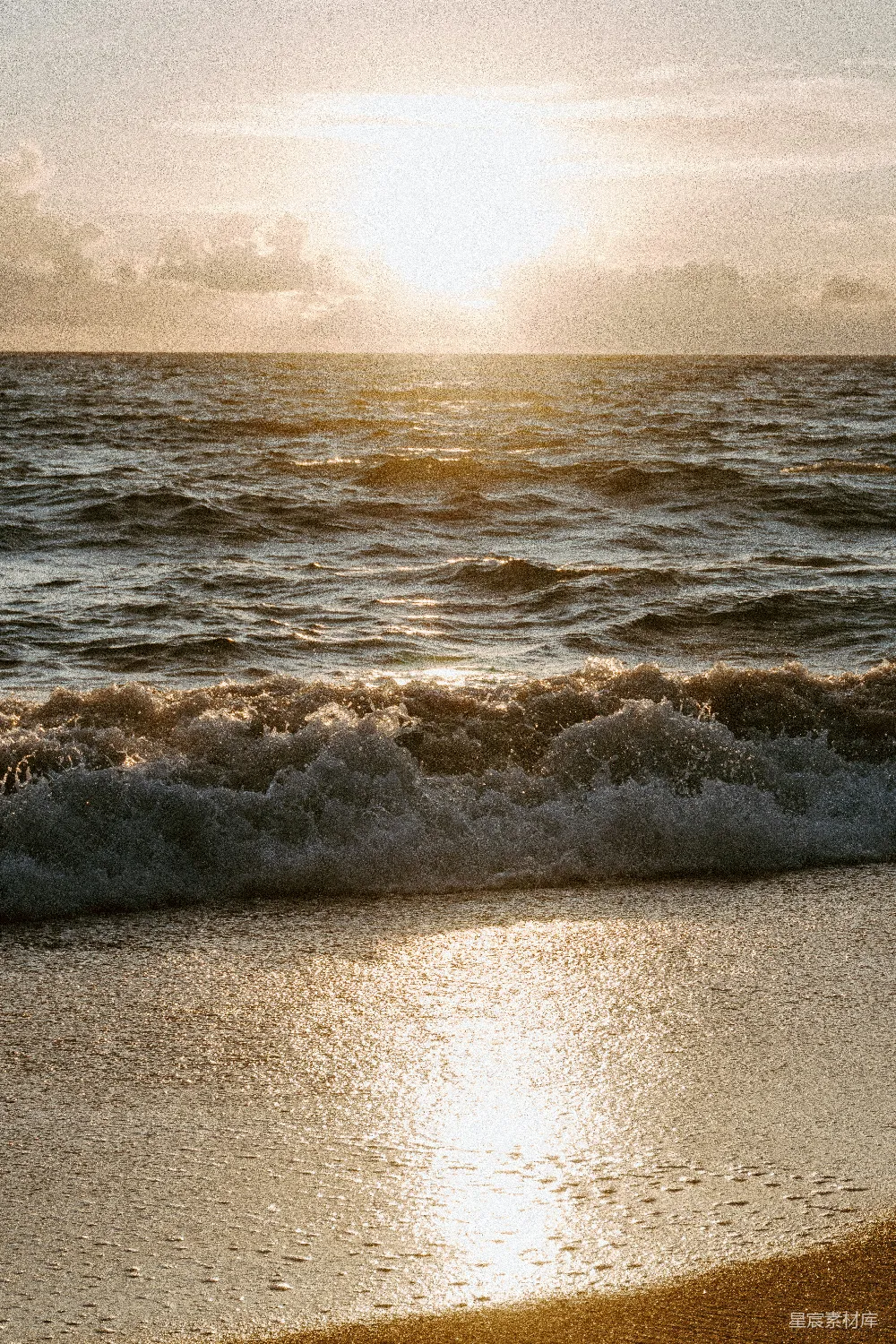 高清摄影  夕阳映照在海浪上，海浪拍打着沙滩。