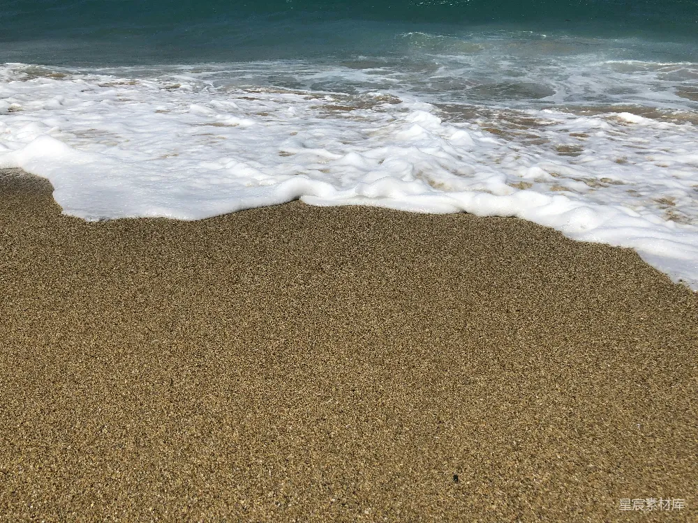 高清摄影  一个沙滩，海浪正拍打着岸边。