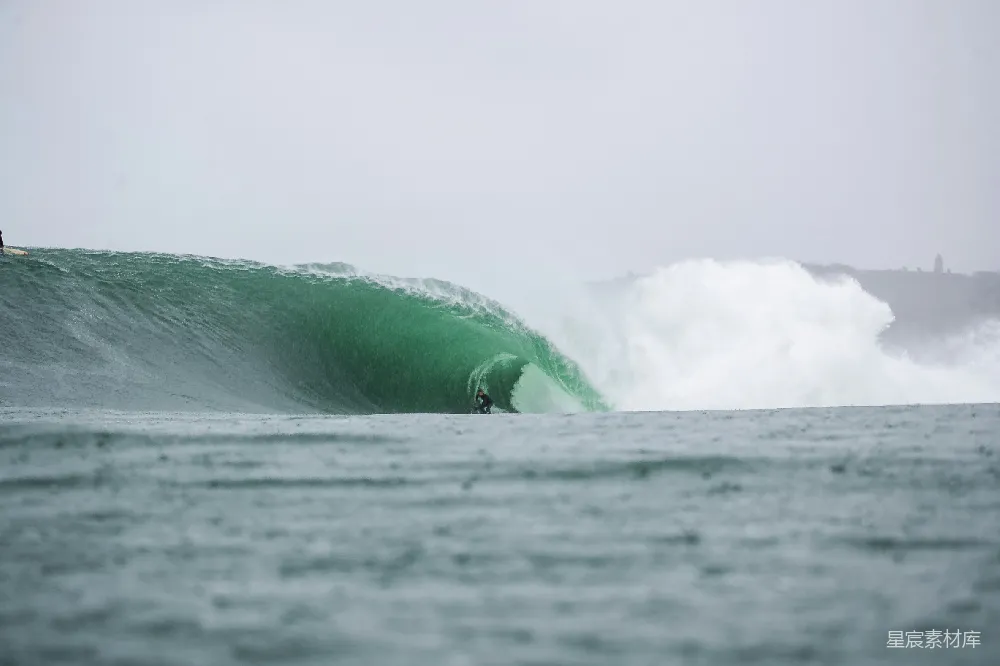 高清摄影  冲浪者在巨大的绿色波浪中滑行。