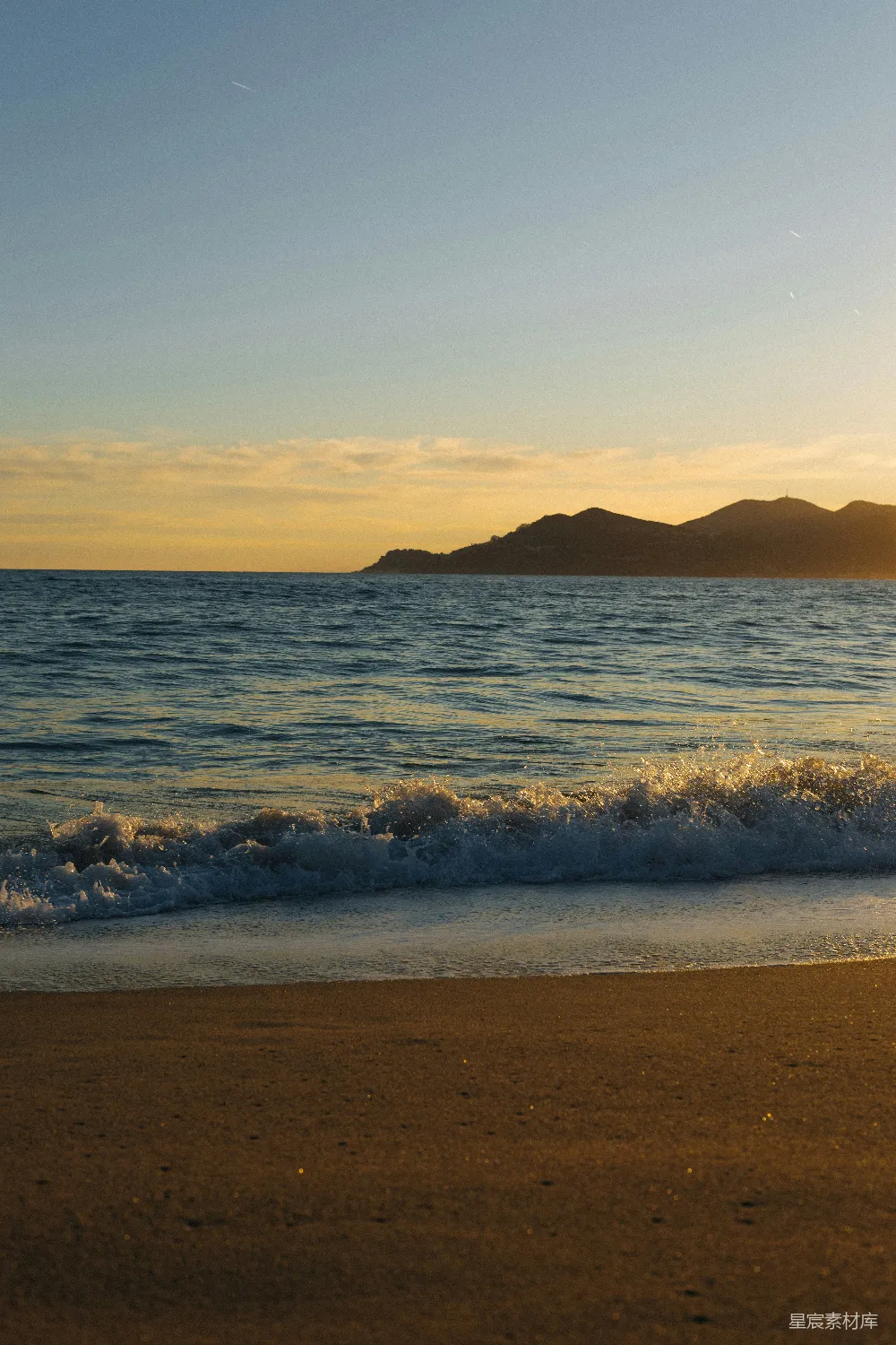 高清摄影  夕阳下，海浪拍打着沙滩。