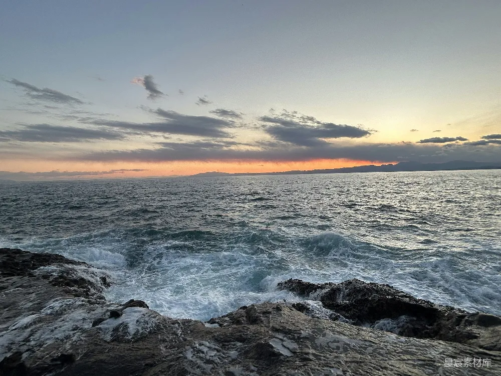 高清摄影  夕阳洒在海浪之上，海岸线布满岩石。