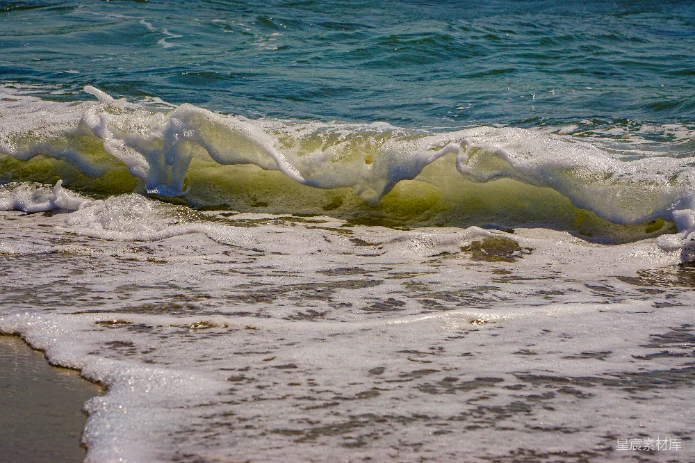 高清摄影  海浪拍打着海滩，背景中有一块冲浪板。