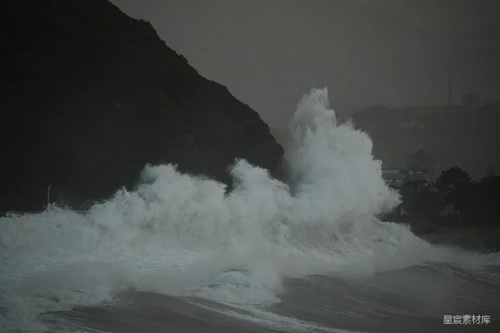 高清摄影  一个巨大的海浪冲向海滩岸边。