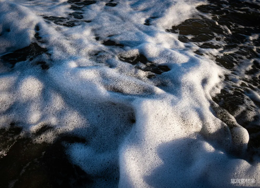 高清摄影  一个被雪覆盖的海滩紧挨着海洋。