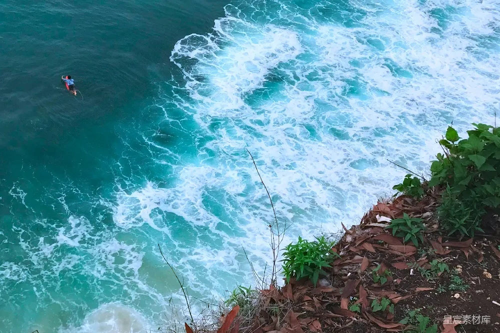 高清摄影  一个男人骑着冲浪板在海洋中的波浪上。