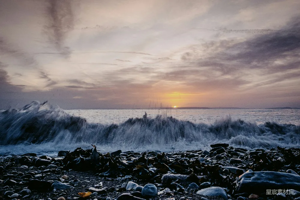高清摄影  夕阳正落下海面，波浪拍打着沙滩。