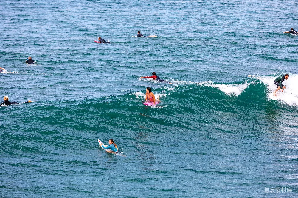 高清摄影  一群人在海浪上骑着冲浪板。