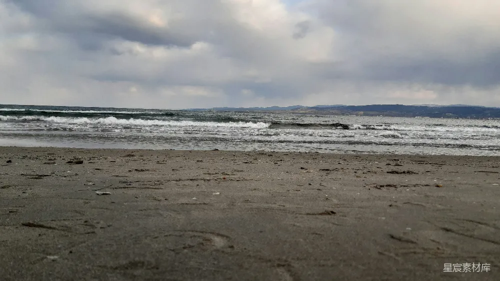 高清摄影  一个沙滩，海浪冲向岸边。