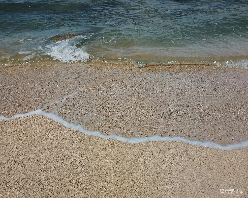 高清摄影  一个沙滩上，海浪在水中进出。