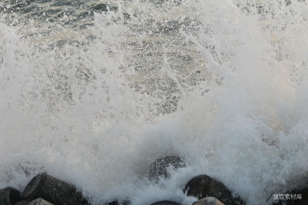 高清摄影  海浪拍打着岩石，形成白色的浪花和泡沫。