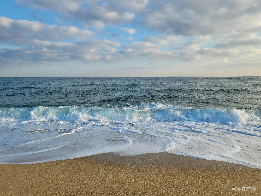 高清摄影  一个沙滩上，海浪拍打着海岸线。
