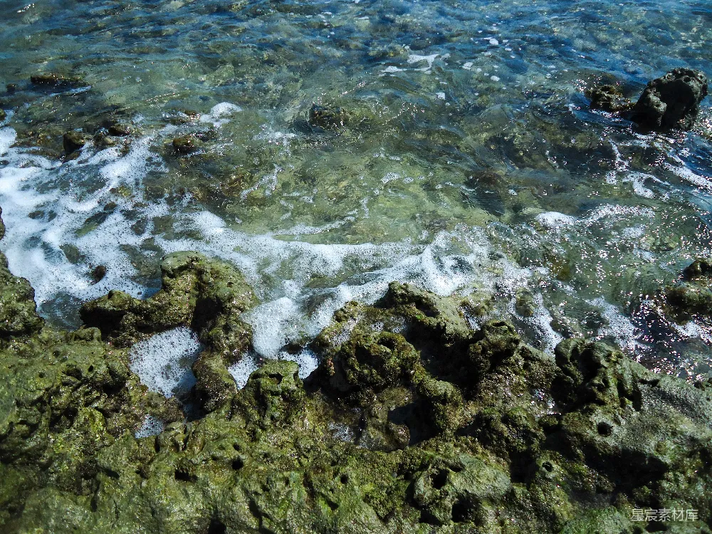 高清摄影  波浪轻轻地拍打着布满青苔的岩石海岸。