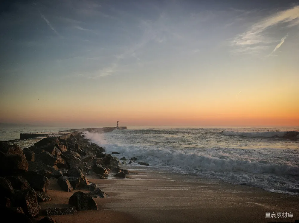 高清摄影  夕阳正缓缓落向海面，远处有一座灯塔。