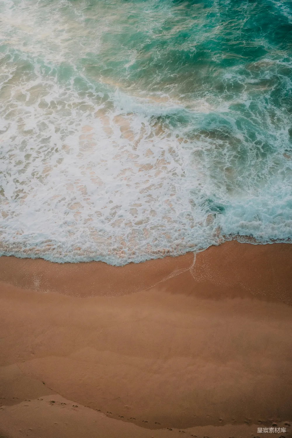 高清摄影  海滩的航拍视角，海浪正涌向岸边。